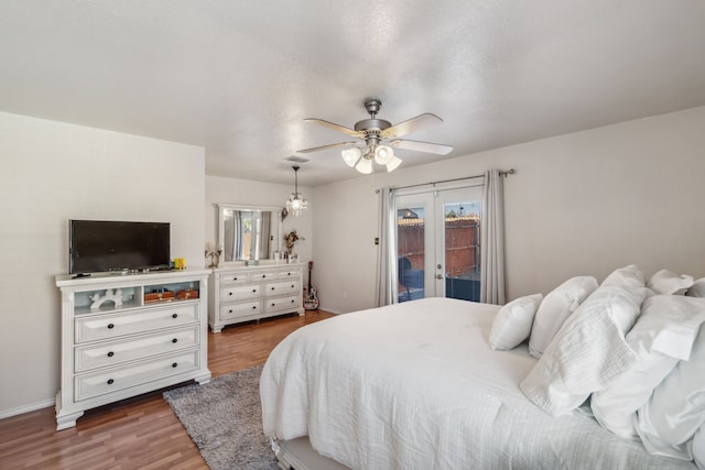 bedroom featuring dark wood-type flooring, access to exterior, ceiling fan, and french doors