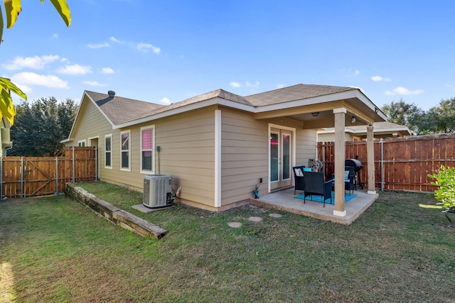 back of house featuring cooling unit, a patio area, and a lawn