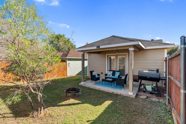 back of house with a yard, a patio, and an outdoor living space with a fire pit