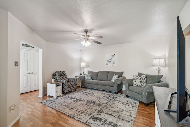 living room featuring hardwood / wood-style flooring, a textured ceiling, and ceiling fan