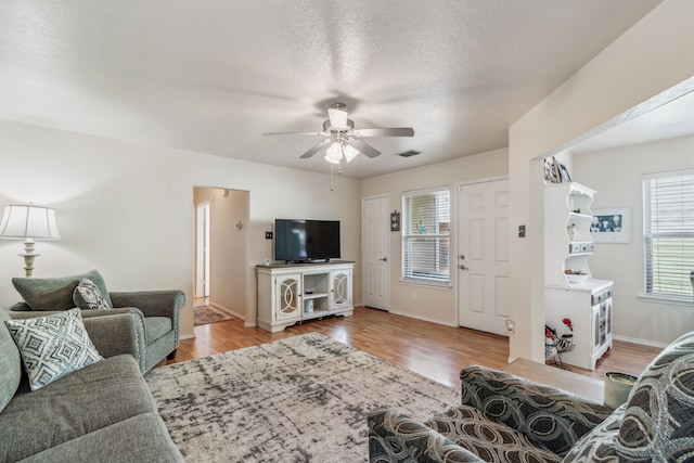 living room with ceiling fan, light hardwood / wood-style floors, and a textured ceiling