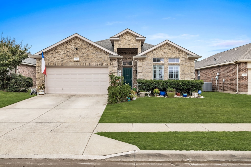 view of front of house featuring a garage, cooling unit, and a front yard