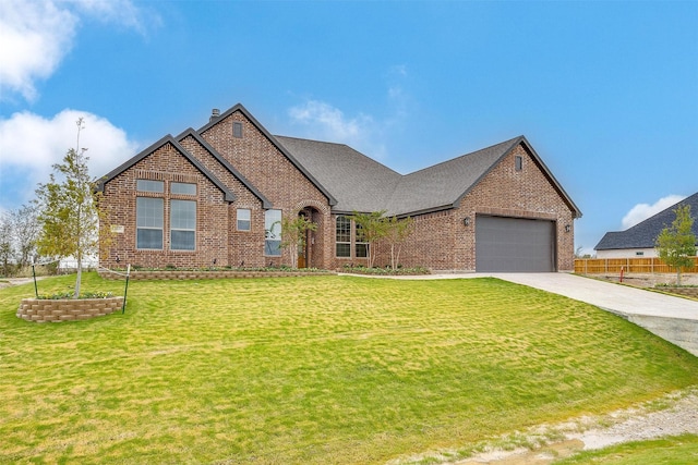 french provincial home featuring a front lawn, fence, concrete driveway, an attached garage, and brick siding