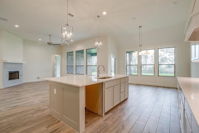 kitchen featuring light hardwood / wood-style floors, sink, ceiling fan, decorative light fixtures, and an island with sink