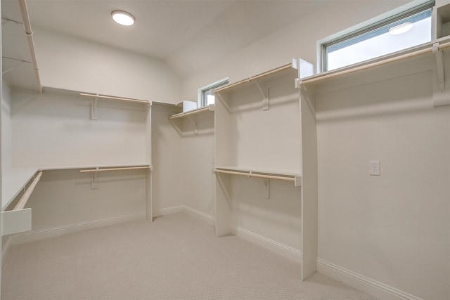 spacious closet with lofted ceiling and light carpet