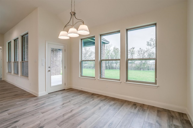 unfurnished dining area with an inviting chandelier and light hardwood / wood-style flooring