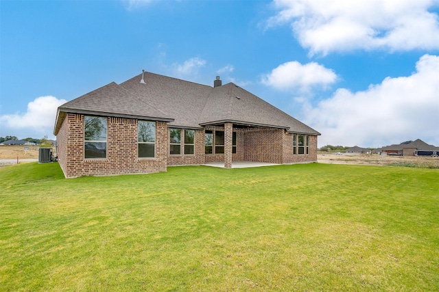 back of house featuring a patio area, a lawn, a shingled roof, and brick siding