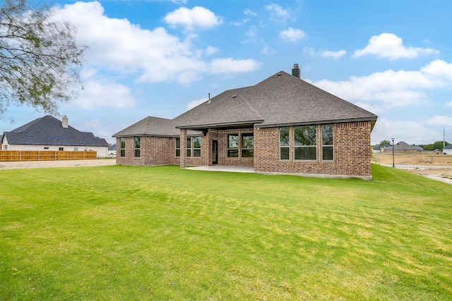 back of house featuring brick siding, a patio area, a lawn, and a shingled roof