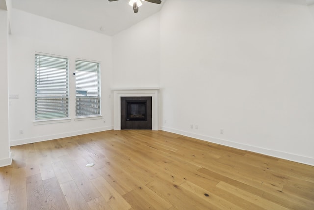 unfurnished living room with ceiling fan, light wood-type flooring, and lofted ceiling