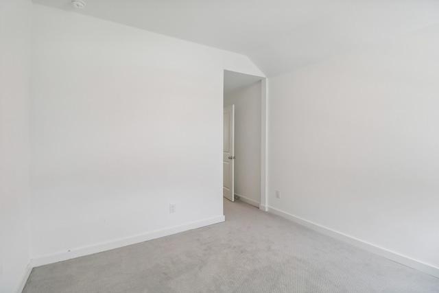 empty room with light colored carpet and vaulted ceiling