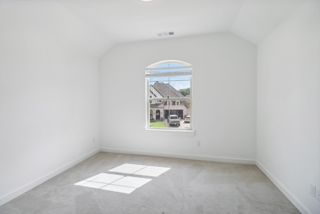 spare room featuring vaulted ceiling and light carpet