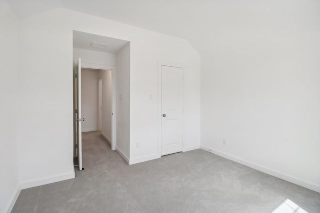 unfurnished bedroom with light colored carpet and vaulted ceiling