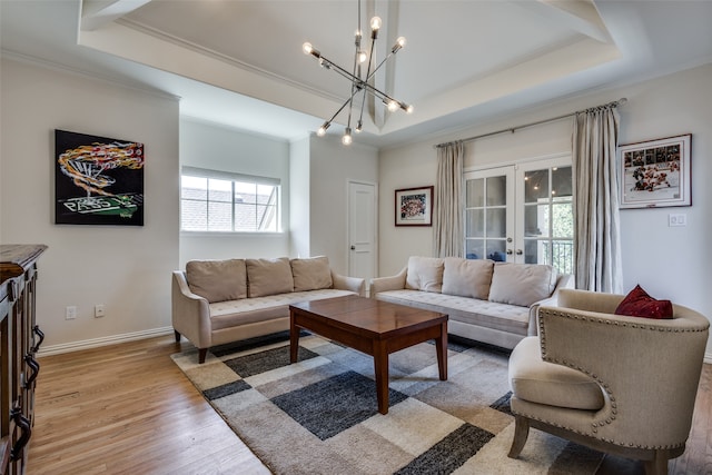 living room featuring ornamental molding, french doors, light hardwood / wood-style flooring, and a raised ceiling