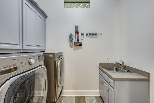 laundry area featuring cabinets, washer and clothes dryer, and sink