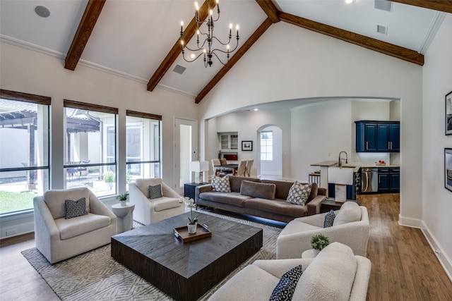 living room featuring high vaulted ceiling, a wealth of natural light, an inviting chandelier, and light hardwood / wood-style flooring