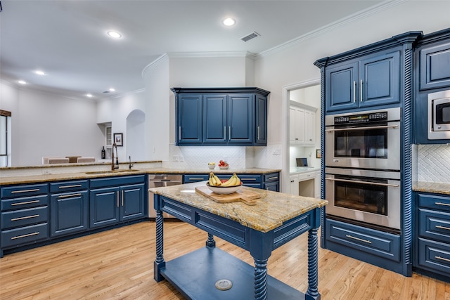 kitchen featuring stainless steel appliances, blue cabinetry, and light hardwood / wood-style flooring