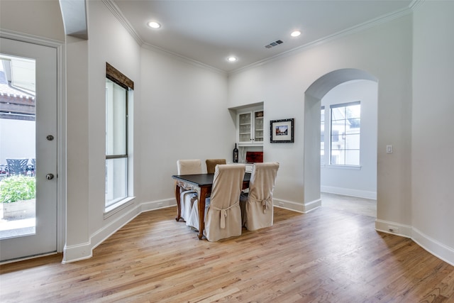 dining room with a healthy amount of sunlight, light hardwood / wood-style flooring, and ornamental molding