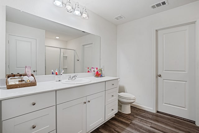 bathroom featuring hardwood / wood-style floors, vanity, toilet, and a shower with shower door