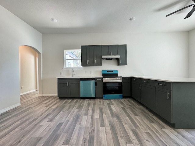 209 Smith St, Hillsboro, TX 76645 - kitchen featuring appliances with stainless steel finishes, under cabinet range hood, arched walkways, a ceiling fan, and light wood-type flooring