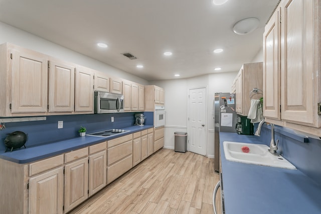 kitchen featuring light brown cabinets, white appliances, sink, and light wood-type flooring