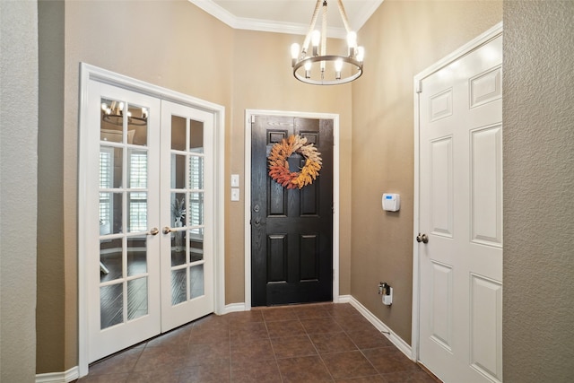 foyer with dark tile patterned floors, french doors, a notable chandelier, and ornamental molding