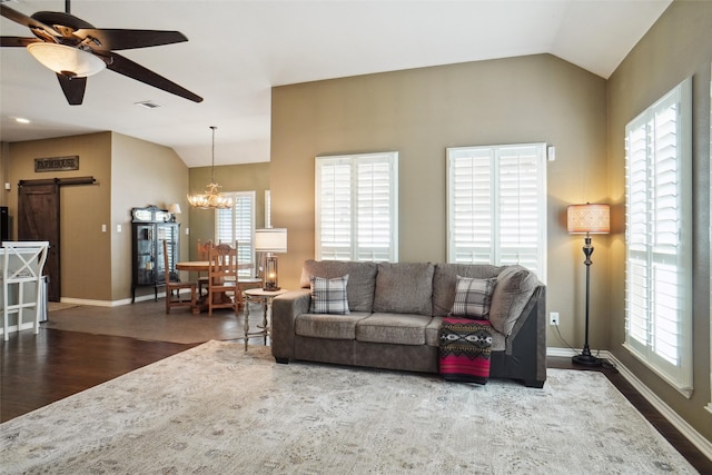 living room with a barn door, a wealth of natural light, lofted ceiling, and dark hardwood / wood-style flooring