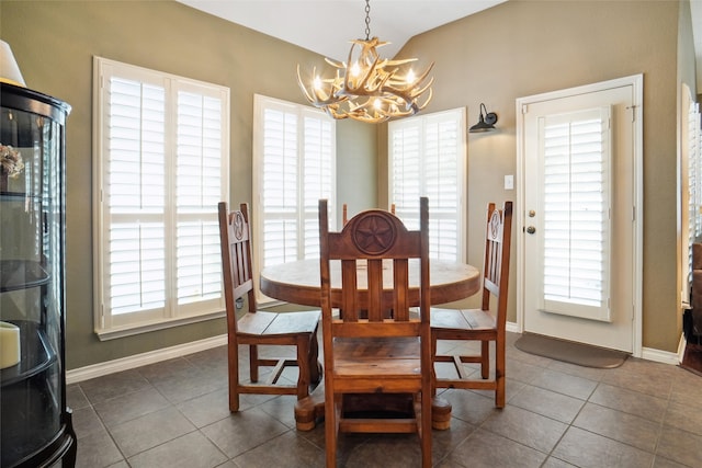 dining area with dark tile patterned flooring, a chandelier, and vaulted ceiling