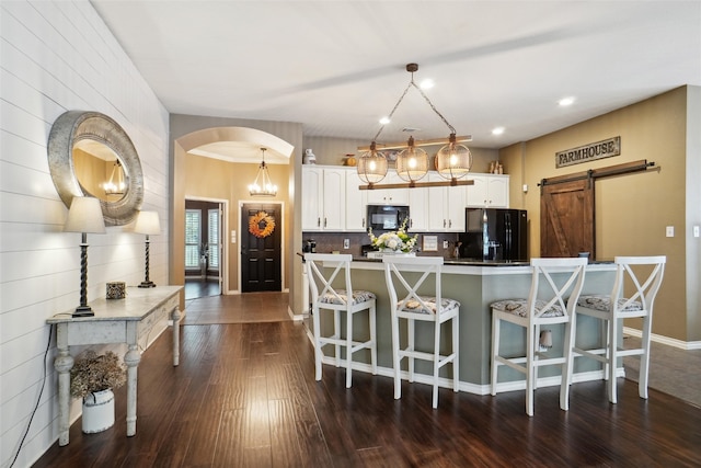 kitchen featuring black appliances, white cabinetry, decorative light fixtures, a barn door, and dark hardwood / wood-style flooring