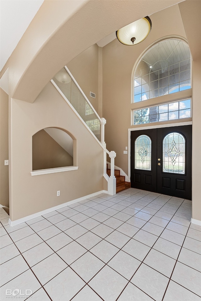 entrance foyer featuring french doors, a towering ceiling, and light tile patterned flooring