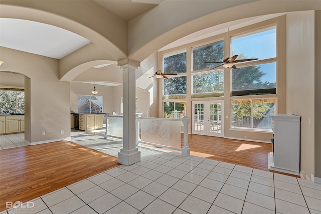 unfurnished living room featuring light wood-type flooring, french doors, ceiling fan, and decorative columns