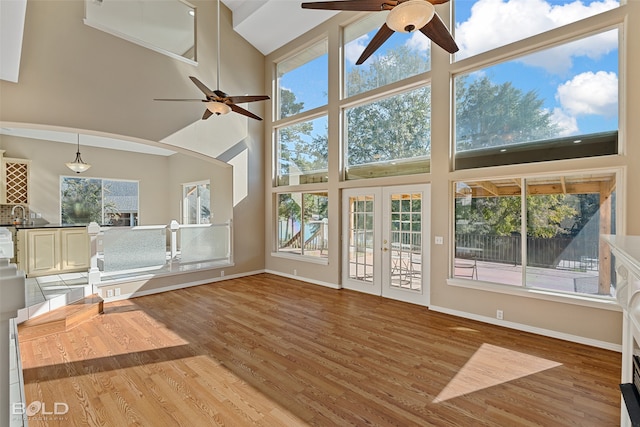 unfurnished living room with high vaulted ceiling, wood-type flooring, ceiling fan, and french doors