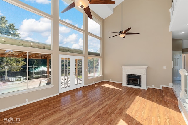 unfurnished living room with light hardwood / wood-style floors, ceiling fan, and a high ceiling