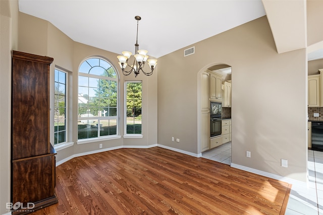 unfurnished dining area featuring an inviting chandelier and light wood-type flooring