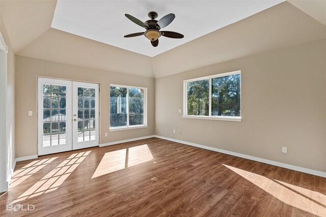 empty room featuring hardwood / wood-style floors, vaulted ceiling, ceiling fan, and french doors