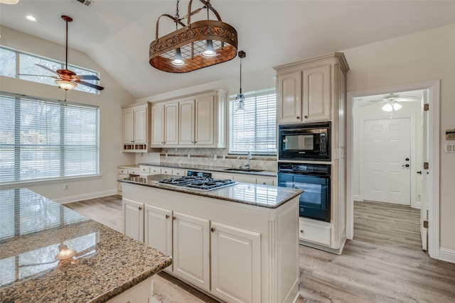 kitchen with black appliances, light stone countertops, ceiling fan, and plenty of natural light