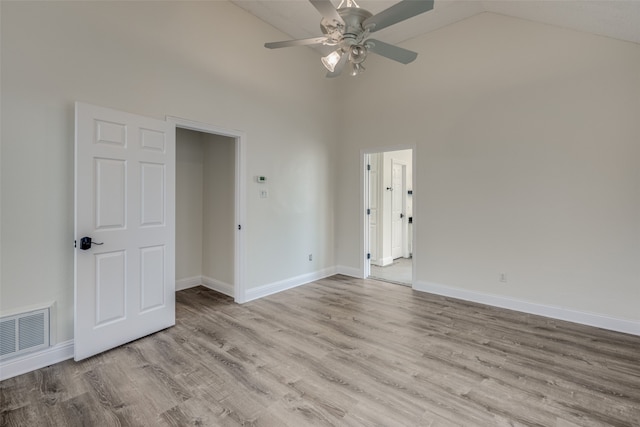 unfurnished room with ceiling fan, light wood-type flooring, and high vaulted ceiling