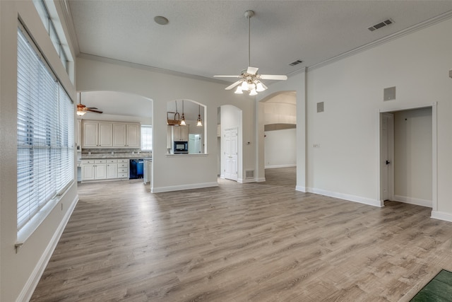 unfurnished living room featuring a healthy amount of sunlight, ceiling fan, and crown molding