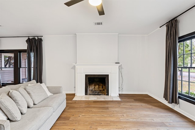 living room featuring ceiling fan, ornamental molding, and light wood-type flooring