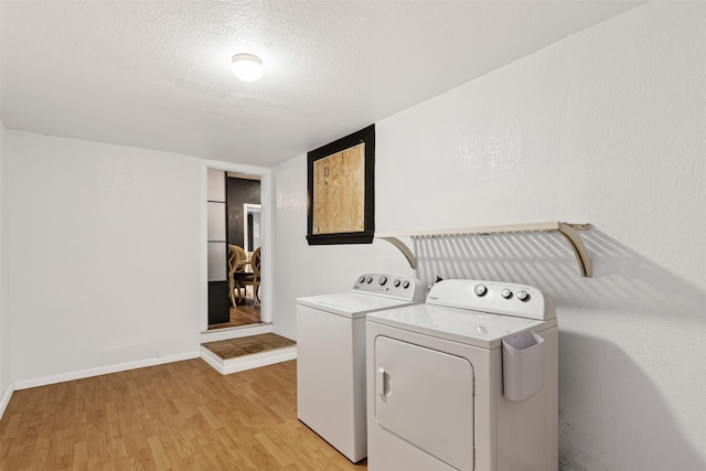 laundry area with washer and dryer, light wood-type flooring, and a textured ceiling