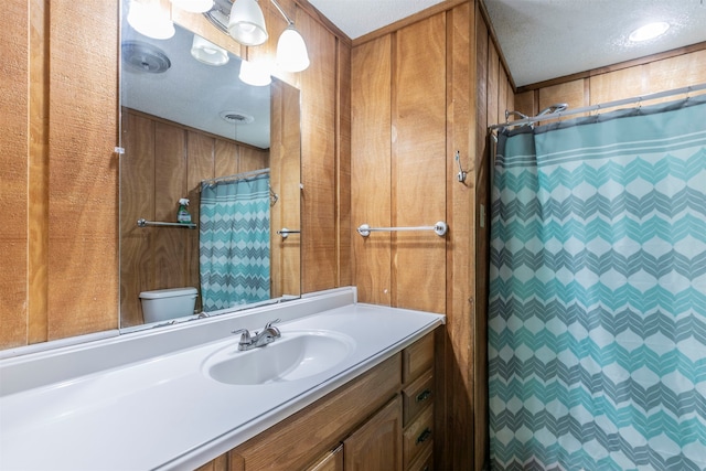 bathroom with vanity, wooden walls, a textured ceiling, and curtained shower