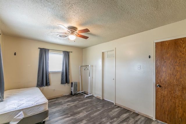 bedroom with radiator, ceiling fan, dark hardwood / wood-style floors, a textured ceiling, and a closet