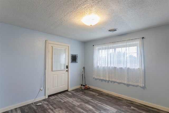 spare room featuring dark wood-type flooring and a textured ceiling