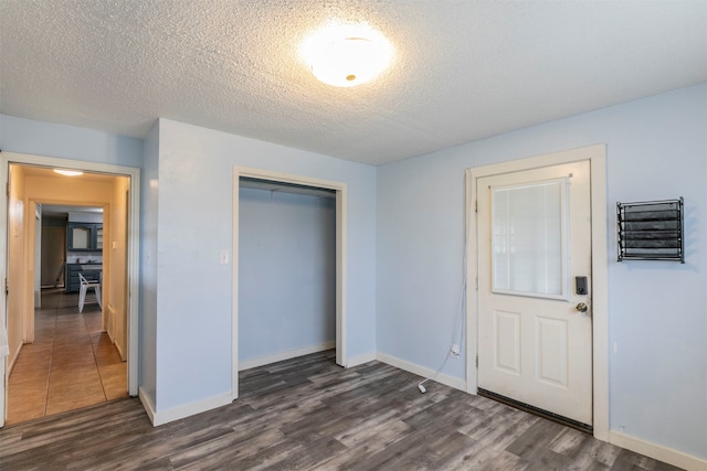 unfurnished bedroom featuring a closet, a textured ceiling, and dark hardwood / wood-style floors