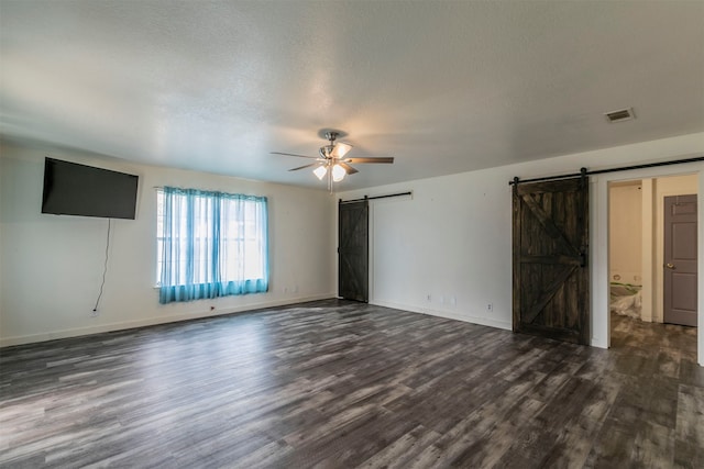 interior space with a barn door, ceiling fan, a textured ceiling, and dark hardwood / wood-style flooring