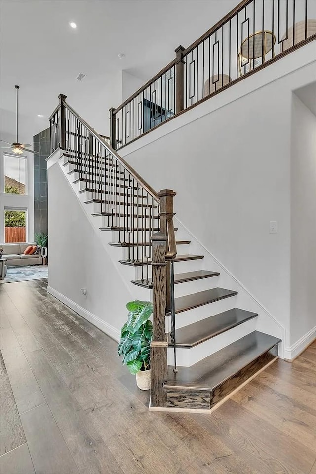 staircase with hardwood / wood-style flooring and ceiling fan