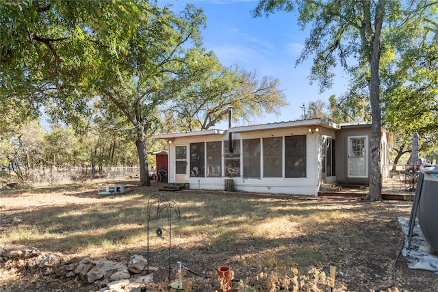 rear view of house with a lawn and a sunroom