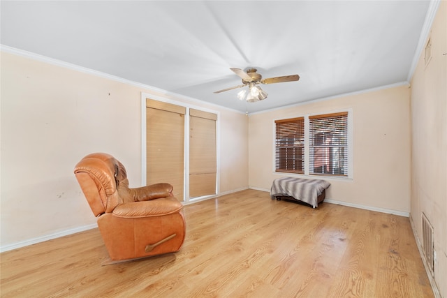 living area featuring light wood-type flooring, ceiling fan, and crown molding