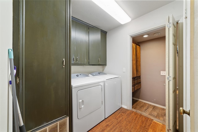 washroom with dark hardwood / wood-style flooring, cabinets, and washer and dryer