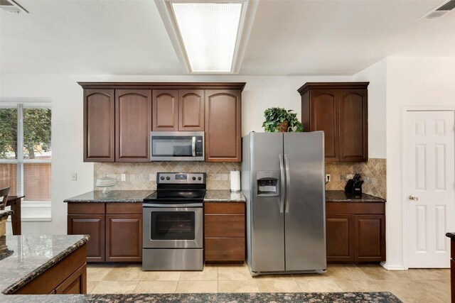 6002 Baldcypress Ct, Garland, TX 75043 - kitchen featuring appliances with stainless steel finishes, dark stone countertops, backsplash, and light tile patterned floors
