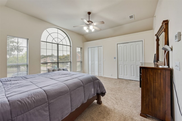 carpeted bedroom featuring two closets, ceiling fan, and lofted ceiling